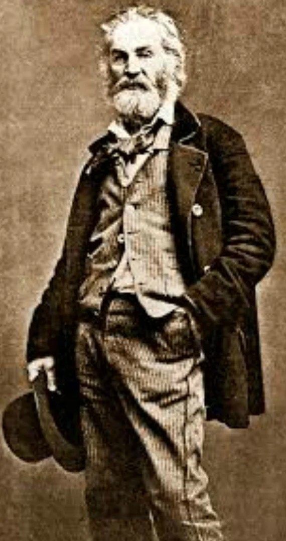 Alton Weagle standing in a field in work clothes, a large pack on his back, setting out on a climb.